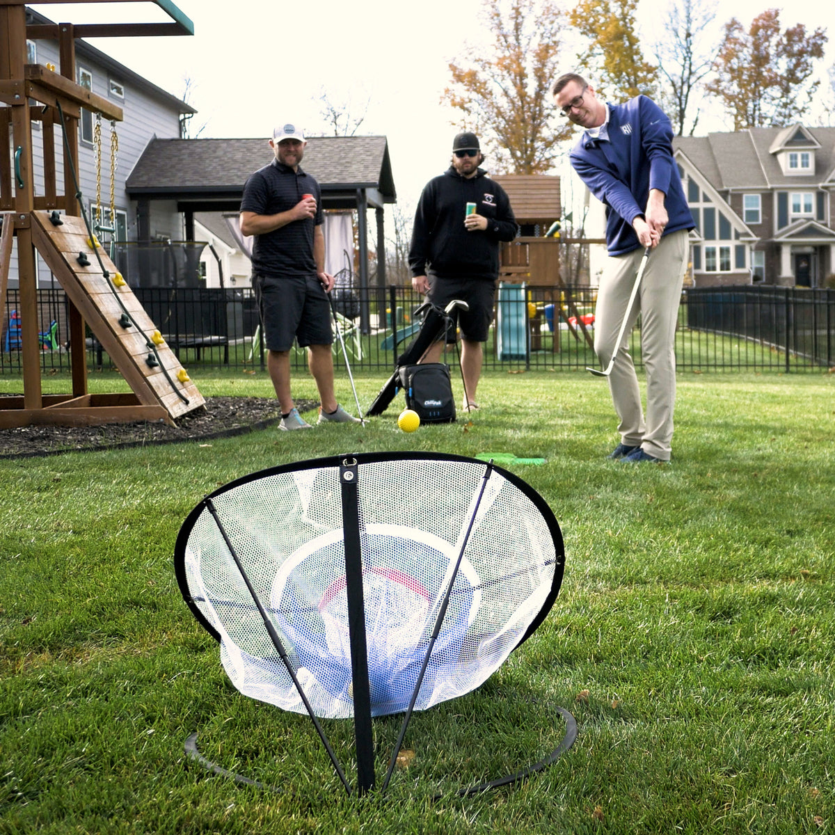 Three people playing Wedge Master on a lawn